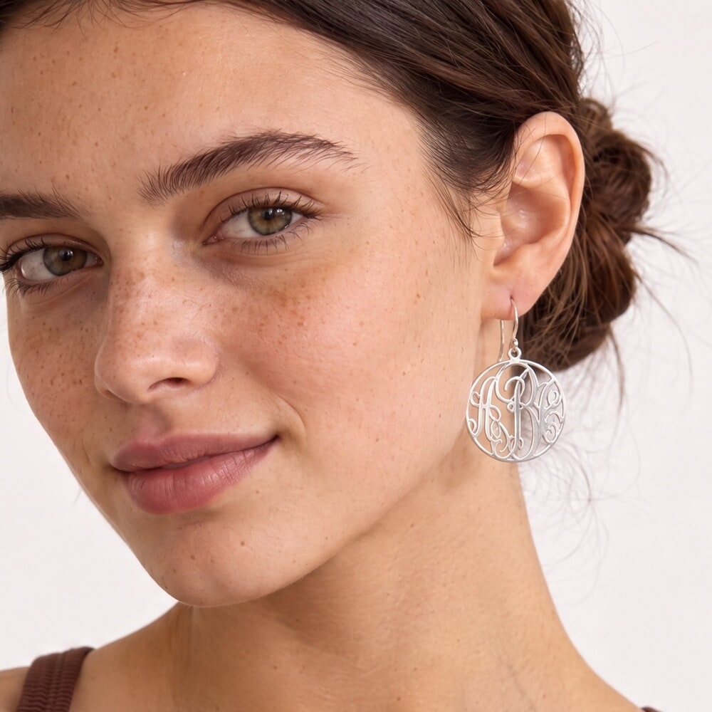 Modelo con pendientes monograma clásicos, destacando su diseño colgante y elegante