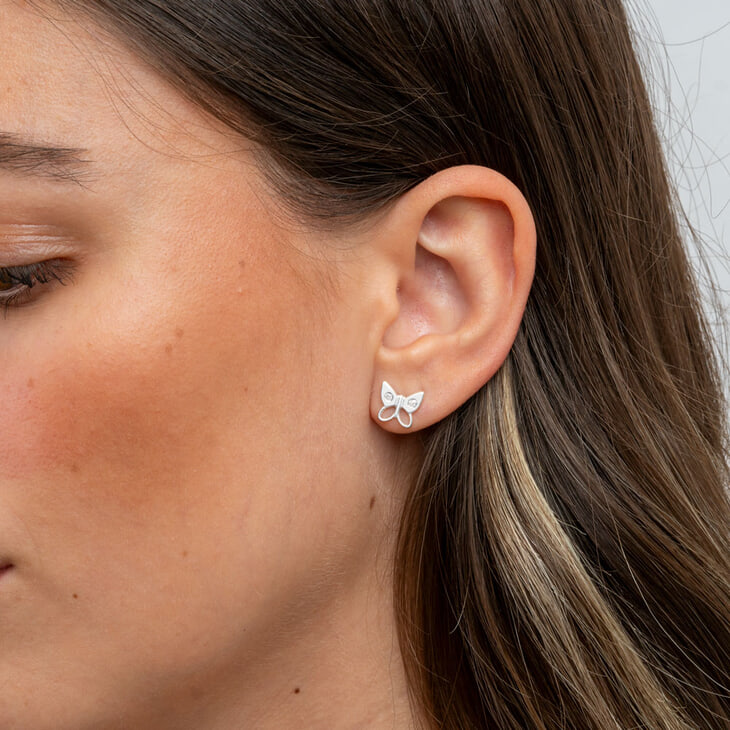 Zoom sur des boucles d'oreilles papillon en zircon cubique sur l'oreille d'un modèle