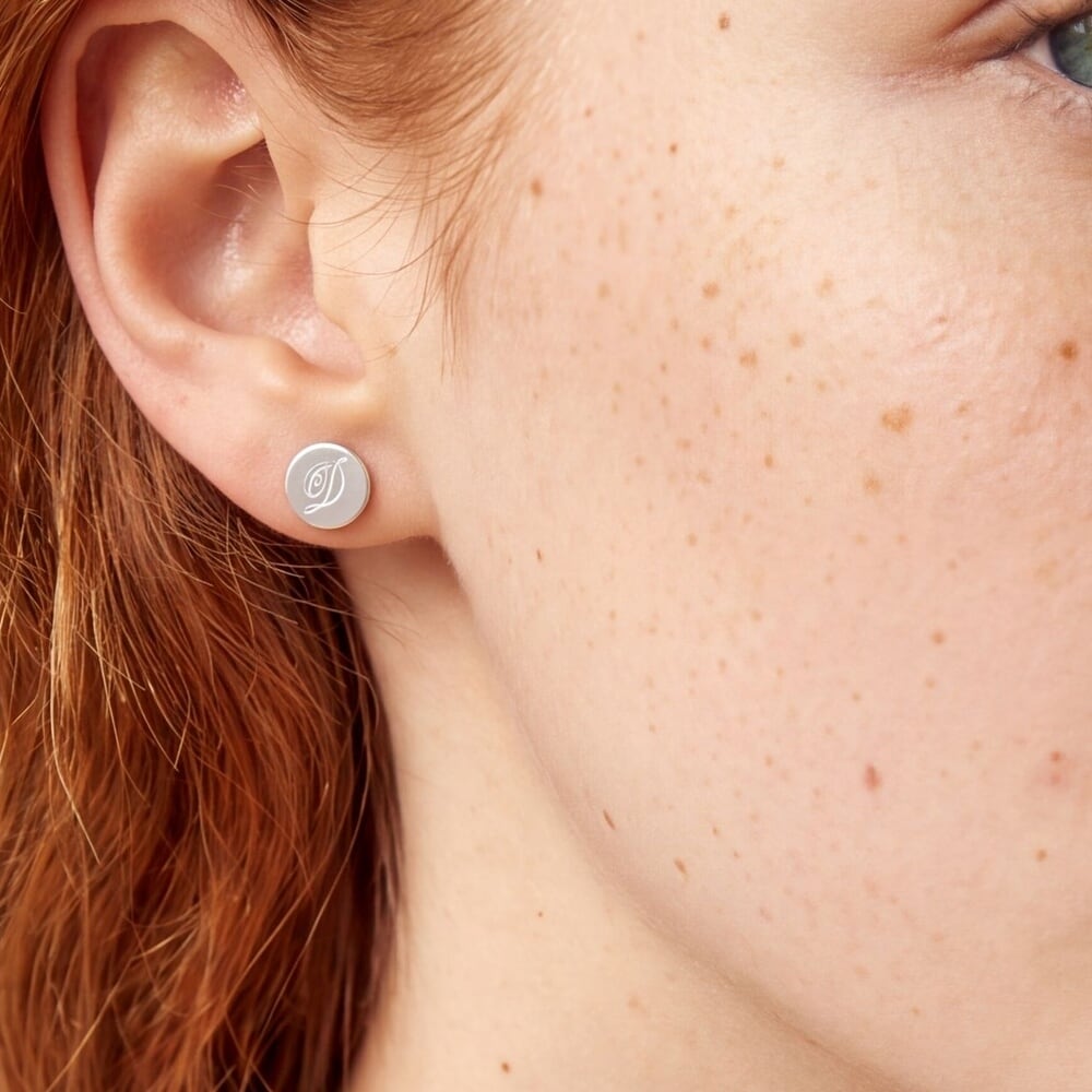 Vue rapprochée d'un modèle portant des boucles d'oreilles initiales