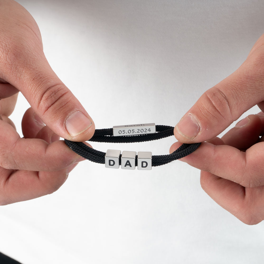 Close-up of hands examining different jewelry pieces and engraving options on a crafting table with design tools
