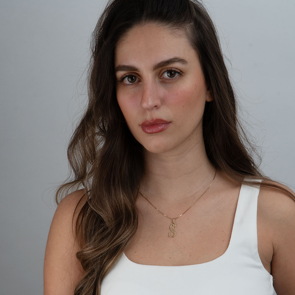 Woman wearing a layered initial necklace look with multiple chain lengths