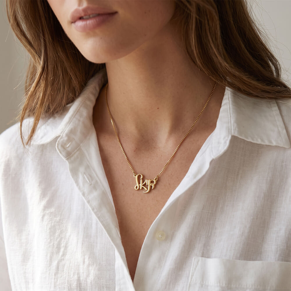 Model showcases Hebrew name necklace in elegant Ahava script, styled with a casual white shirt.