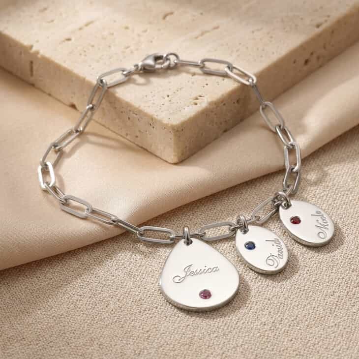 Personalized silver name charm bracelet with birthstone, featuring multiple engraved name pendants.