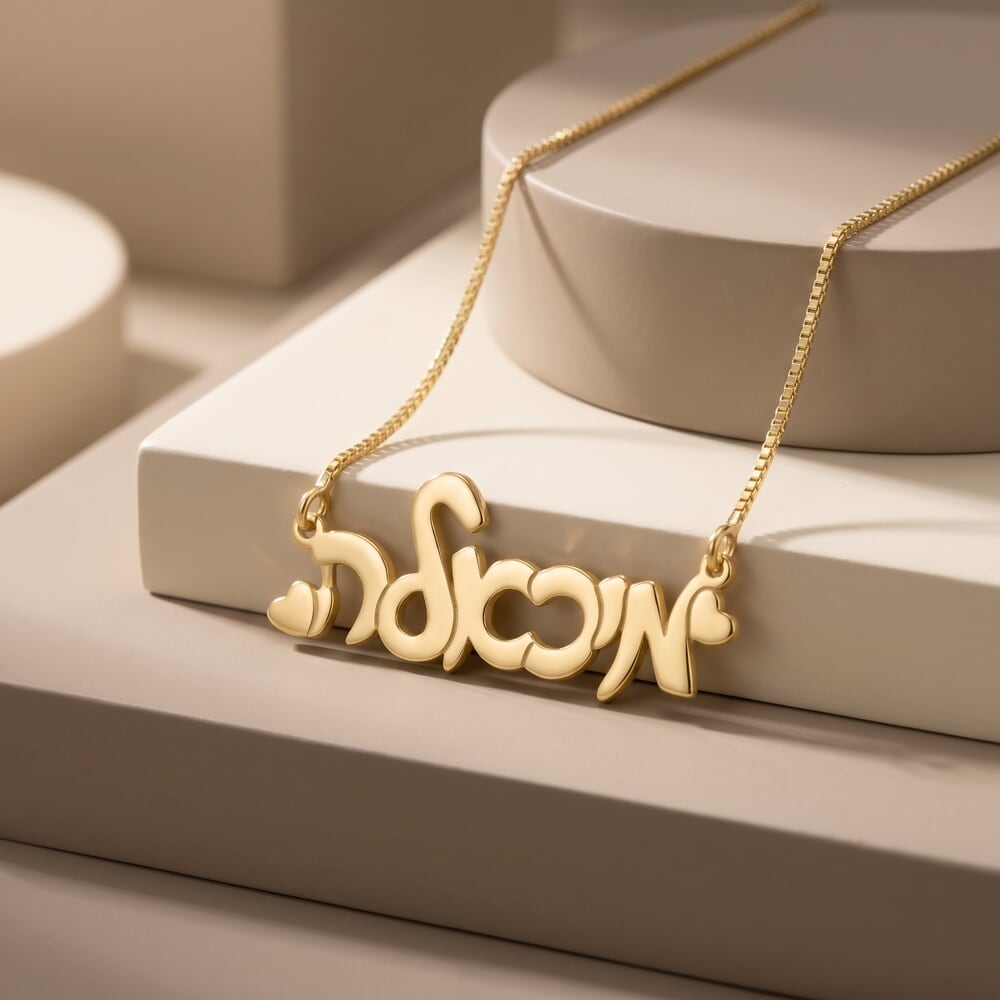 Model wearing a Hebrew cursive name necklace with hearts, styled against a soft background