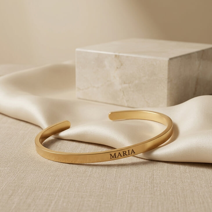 Personalized Thin Open Bangle Bracelet on a soft fabric background with engraved name 'MARIA'