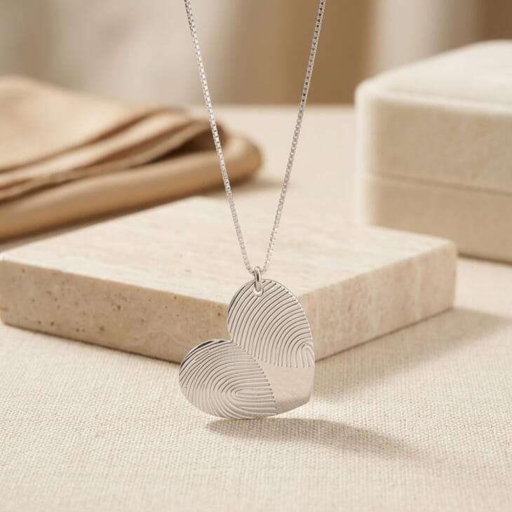 Close-up of the Personalized Double Fingerprint Heart Necklace on a textured background, showcasing its unique design.
