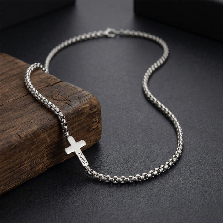 Collar cruz lateral personalizado en plata sobre una superficie de madera