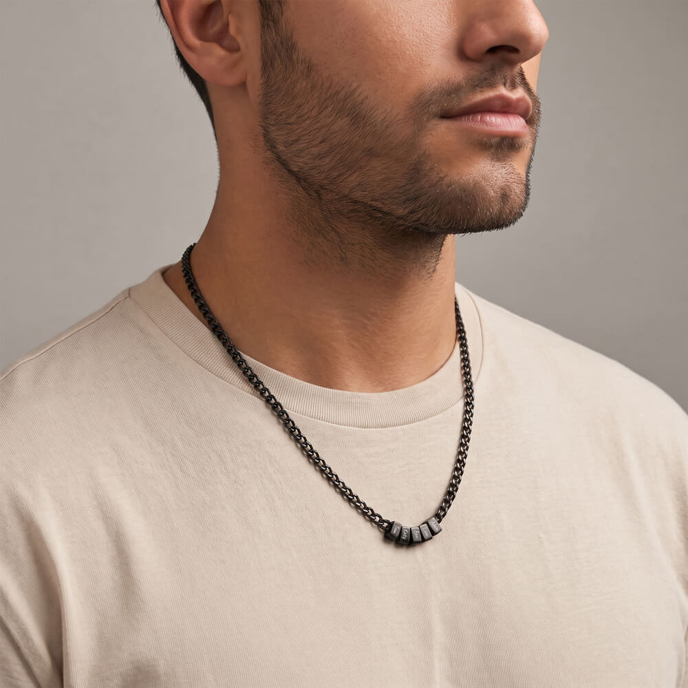 Man displaying a personalized black dad necklace featuring engraved names in a relaxed outfit
