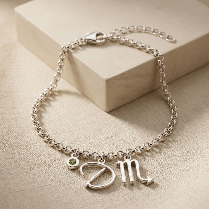 Close-up of zodiac script initial and birthstone charms on a bracelet