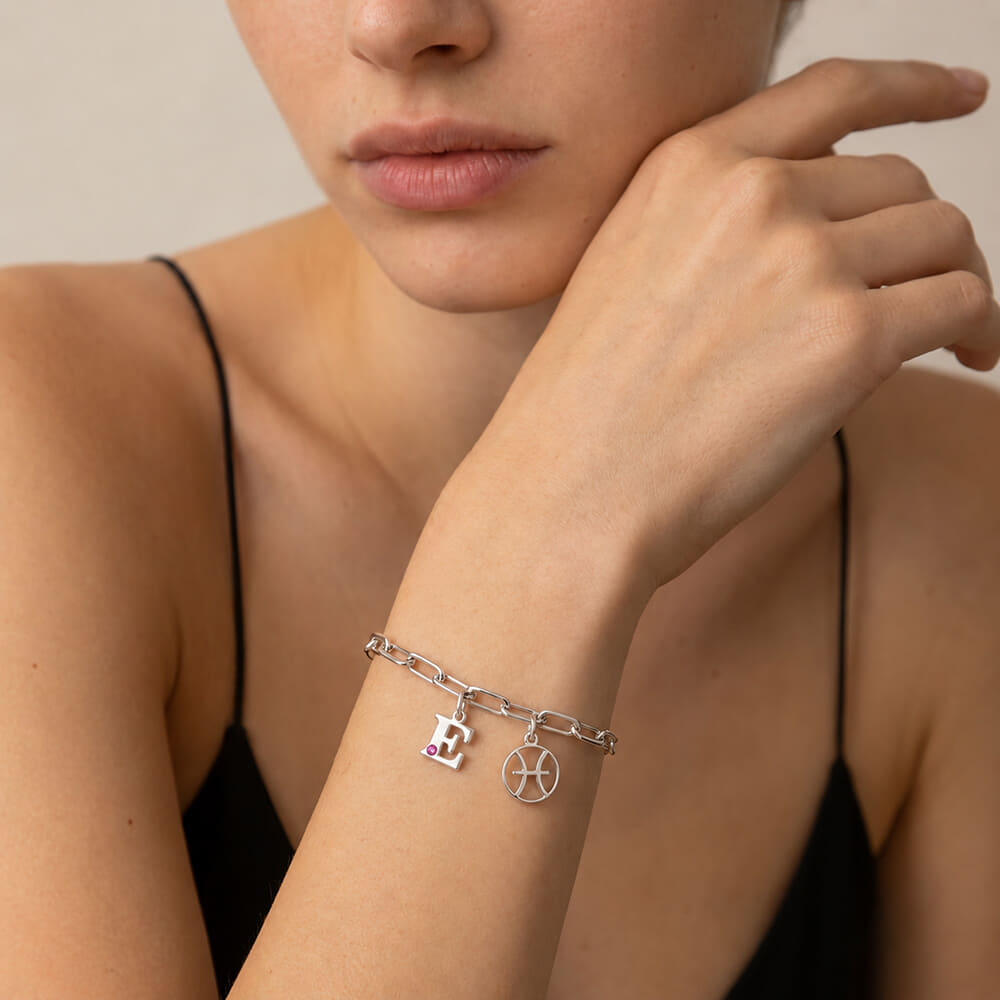 Model showcasing Circle Zodiac and Initial Bracelet with pink birthstone in a stylish pose