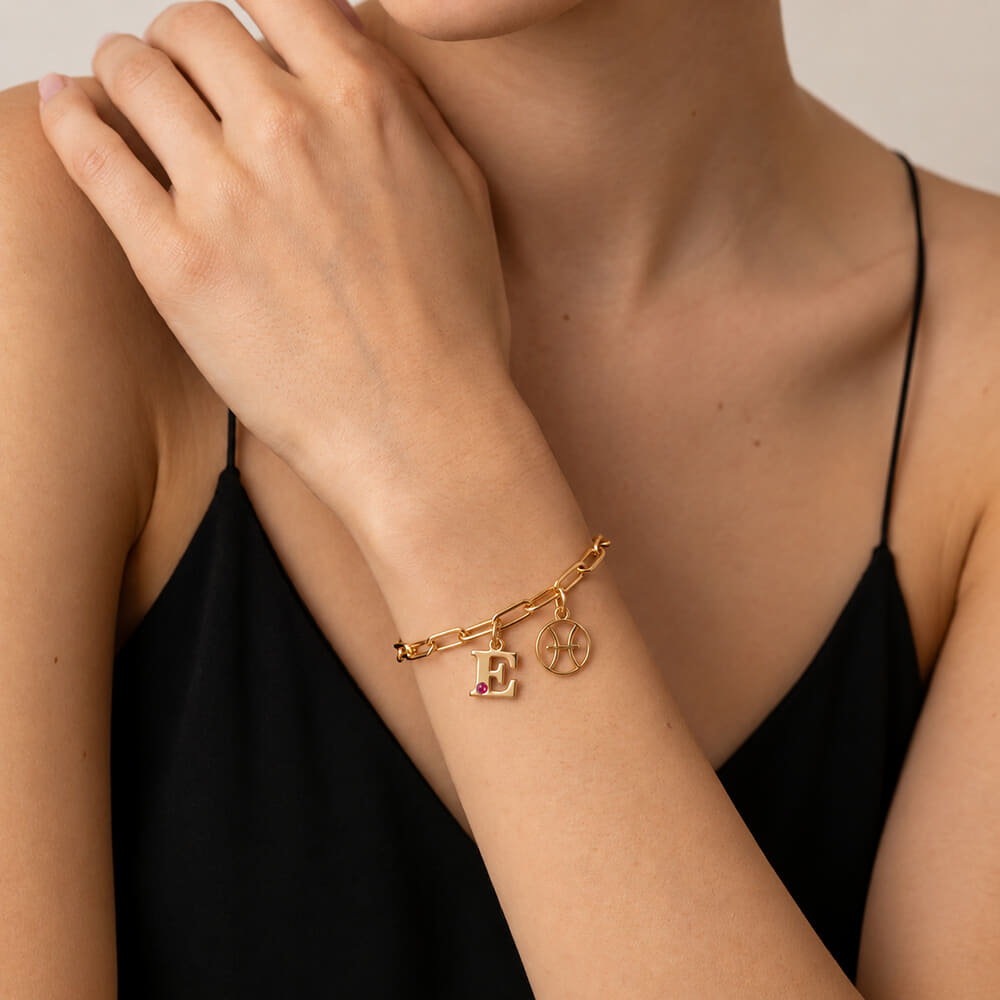 Model wearing Circle Zodiac and Initial Bracelet with red birthstone charm on wrist