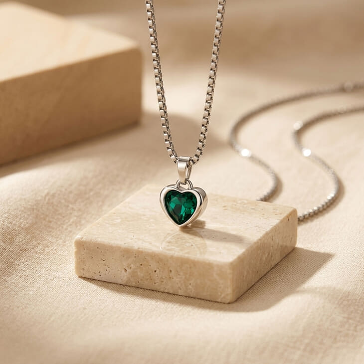Heart gemstone necklace with a striking green heart stone on a natural fabric