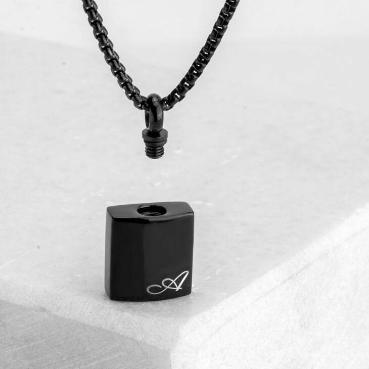 Collar urna negra personalizado en plata, exhibido de manera elegante sobre fondo claro